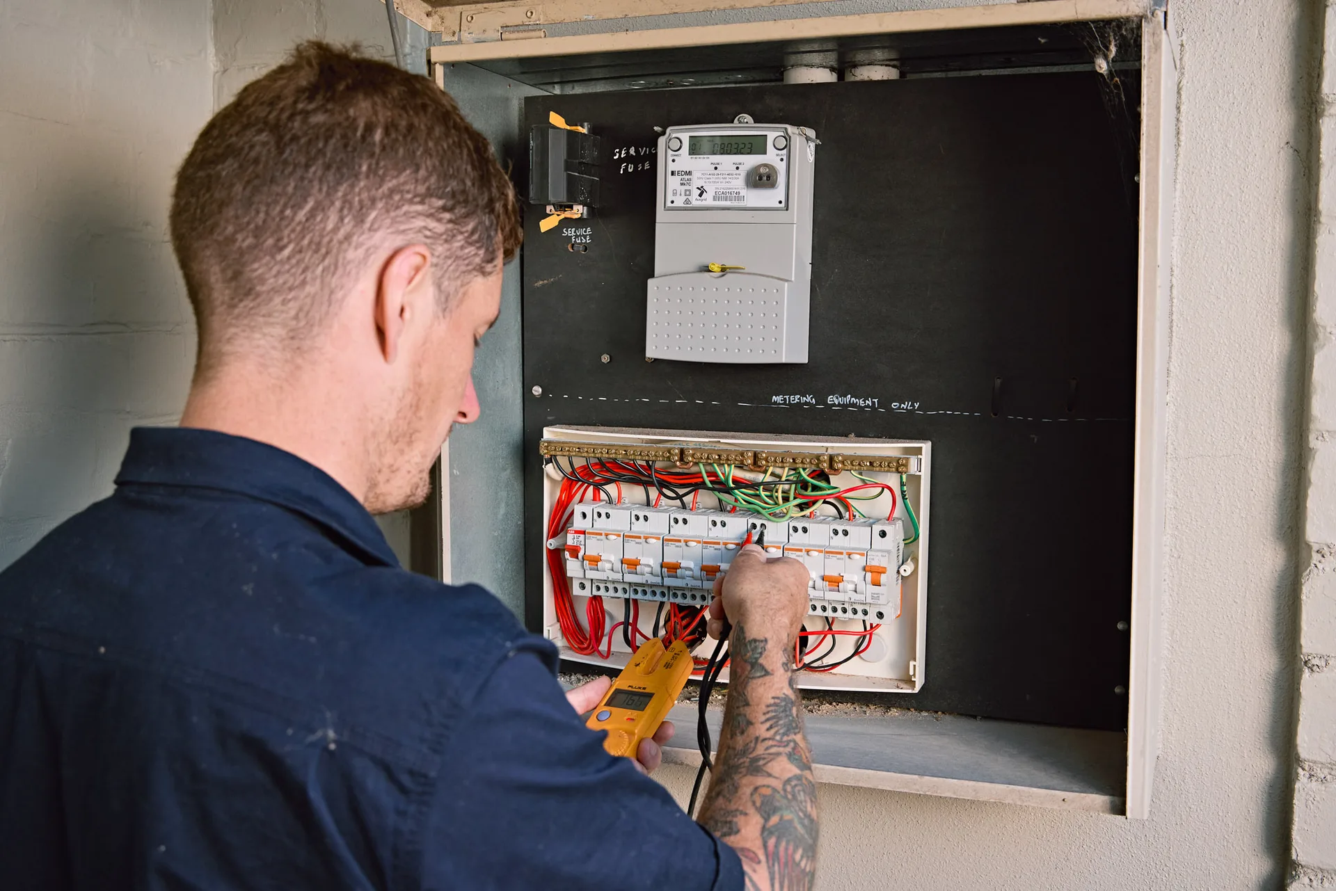 Electrician testing circuits in a switchboard with a multimeter